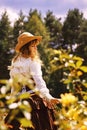 Beautiful girl in a hat in a vintage dress with roses. Summertime park