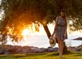 Beautiful girl in a hat walks along the seashore at sunset in a dress Royalty Free Stock Photo