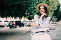 Beautiful girl in a hat in a white t-shirt and hat posing on a scooter Royalty Free Stock Photo