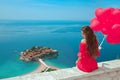 Beautiful girl with heart balloons over Sveti Stefan island in B