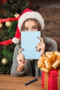 Beautiful girl hiding behind New Year and Christmas postcard Royalty Free Stock Photo