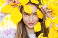 Beautiful girl hiding her face behind an autumn leafs, Cheerful woman hides face autumn yellow leaf wearing close up, autumn Royalty Free Stock Photo