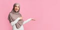 Beautiful girl in hijab pointing at something on her empty palm