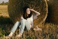 Beautiful girl hipster looks distance against hay bale in fall