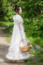 Beautiful girl in an historical bride dress with a wicker basket in her hands Royalty Free Stock Photo