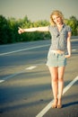 Beautiful girl hitchhiking on the road Royalty Free Stock Photo