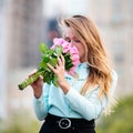 Beautiful girl holding bouquet of pink roses flowers on dating in the city. Royalty Free Stock Photo