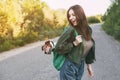 A beautiful girl is holding a green backpack on her shoulder, from which a cute dog looks out. A girl and her friend travel Royalty Free Stock Photo