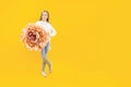 A beautiful girl holding a huge peony flower in her hands on a yellow background. Beautiful bud Royalty Free Stock Photo