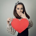 Beautiful girl holding large paper red heart and closing her mouth with hand. Heartbreaker. Temptress. Seductive woman. Portrait Royalty Free Stock Photo