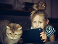 Beautiful girl holding a Tablet and looks at the cat