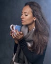 A beautiful girl holds a cup in her hands as the wind blows her long dark brown hair Royalty Free Stock Photo