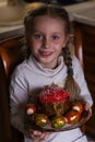 Beautiful girl holds Easter cake and eggs on a plate and smiling at the camera. Easter holiday Royalty Free Stock Photo