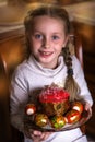 Beautiful girl holds Easter cake and eggs on a plate and smiling at the camera. Easter holiday Royalty Free Stock Photo