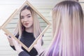 Beautiful girl holds a mirror in her hands, looks in the mirror in a beauty salon. Hair Care