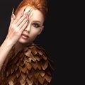 Beautiful girl in the image of the Phoenix with bright makeup, long fingernails and red hair. Beauty face.