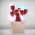 Beautiful girl inside a cardboard box with red ballooons