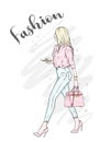 A beautiful girl in jeans, a blouse and in high-heeled shoes. A stylish woman with long hair and a bag. Fashion and style.