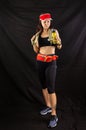 Beautiful girl in jogging red uniform, drinks water after training in the studio on a black background Royalty Free Stock Photo