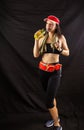 Beautiful girl in jogging red uniform, drinks water after training in the studio on a black background Royalty Free Stock Photo