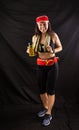 Beautiful girl in jogging red uniform, drinks water after training in the studio on a black background Royalty Free Stock Photo