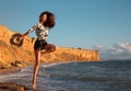 Beautiful Girl Jumping on The Beach at sunset. Summer Vacation Concept. Sexy fashionable brunette woman with straw hat having fun Royalty Free Stock Photo