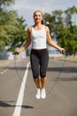 Beautiful girl with a jumping rope. Sports woman jumping on a park background. Active lifestyle concept. Royalty Free Stock Photo