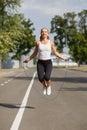 Beautiful girl with a jumping rope. Sports woman jumping on a park background. Active lifestyle concept. Royalty Free Stock Photo