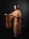 Beautiful girl in kimono with japanese sword katana on a black Royalty Free Stock Photo