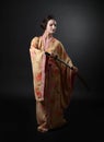 Beautiful girl in kimono with japanese sword katana on a black Royalty Free Stock Photo