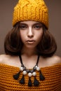 Beautiful girl in a knitted hat on her head and a necklace of pearls around her neck. The model with gentle make-up and gold lips Royalty Free Stock Photo