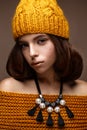 Beautiful girl in a knitted hat on her head and a necklace of pearls around her neck. The model with gentle make-up and gold lips