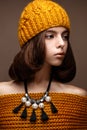 Beautiful girl in a knitted hat on her head and a necklace of pearls around her neck. The model with gentle make-up and gold lips