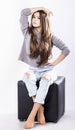 Beautiful girl in a knitted sweater sitting on a black wig on a white background. Long dark hair. torn jeans Royalty Free Stock Photo