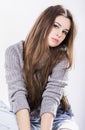 Beautiful girl in a knitted sweater sitting on a black wig on a white background. Long dark hair. torn jeans Royalty Free Stock Photo