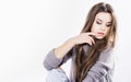 Beautiful girl in a knitted sweater sitting on a black wig on a white background. Long dark hair. torn jeans Royalty Free Stock Photo