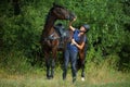 Beautiful girl leading her saddle horse in meadow