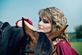 A beautiful girl leaned her elbows on the horse`s