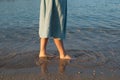 Beautiful girl legs in blue dress is walking on the sea beach. Summer vacation photo Royalty Free Stock Photo