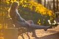 Beautiful girl with light brown hair is sitting on a bench in the alley of an autumn park Royalty Free Stock Photo