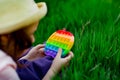 A beautiful girl in a hat, playing with a toy to drink on the green grass.in the park, on a summer day