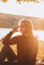 Beautiful girl with long blond hair in autumn landscape at sunset. Autumn portrait of a girl sitting on the grass Royalty Free Stock Photo