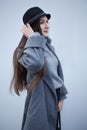 Beautiful girl with long dark hair, black hat, gray long coat posing in the city on the street in autumn Royalty Free Stock Photo