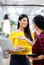 Beautiful girl with long dark hair working on laptop and discussing with her female colleague in a modern business office Royalty Free Stock Photo