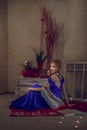 Beautiful girl in long evening dress on the floor near bureau reding book