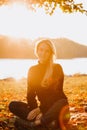 Beautiful girl with long hair in autumn landscape at sunset. Portrait of a girl sitting on the grass, selective focus Royalty Free Stock Photo