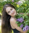 Beautiful girl with long hair in a black top near a blooming lilac Bush Royalty Free Stock Photo