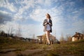 Beautiful girl with long hair in short skirt, white shirt and jacket in village or small town. Tall young slender woman