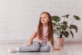 Beautiful girl with long hair sits in a white room on the floor and smiles Royalty Free Stock Photo