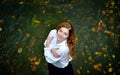 Beautiful girl with long hair in white shirt and black skirt standing in the river with autumn leaves and looking up. Royalty Free Stock Photo